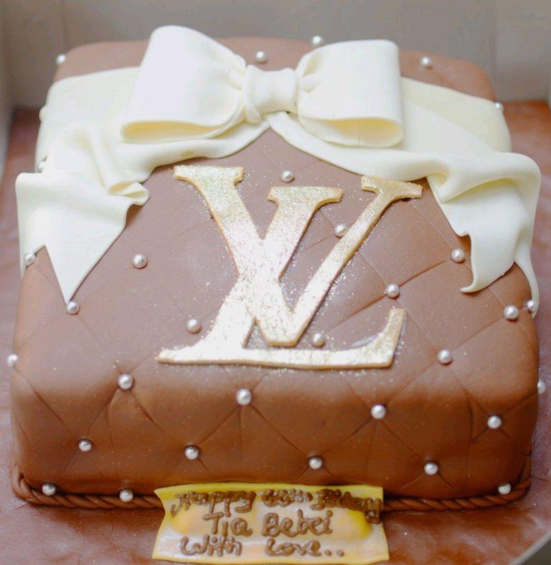 Square brown fondant cake designed like a luxury handbag with a large white bow and gold LV logo.