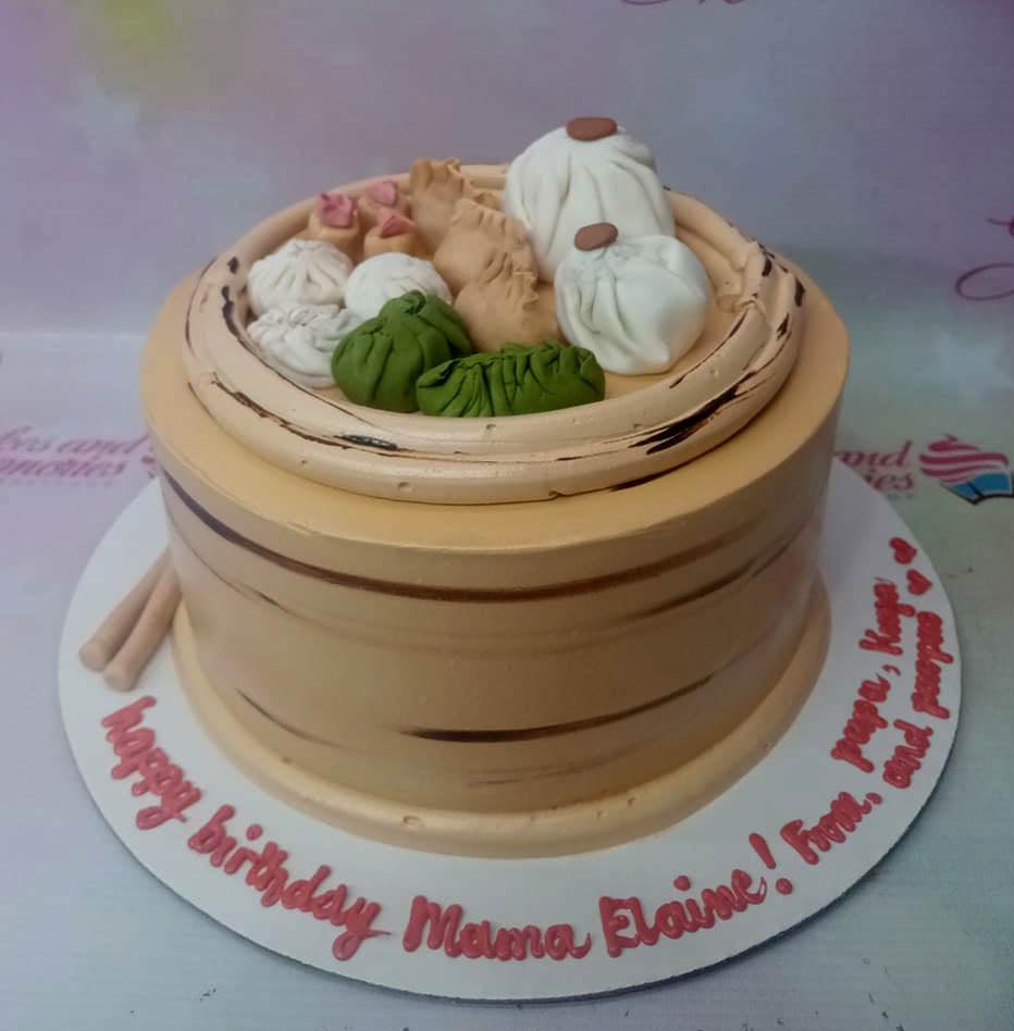 Dim sum themed birthday cake designed as a bamboo steamer basket with fondant dumplings and buns on top.