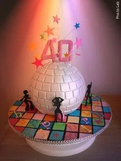 A white disco ball shaped cake on a colorful dance floor base with pink number 40 and star toppers.