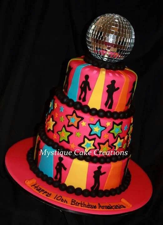 Vibrant 3-tier disco themed birthday cake in pink, orange, yellow, and blue with a large mirror disco ball topper and dancer silhouettes.