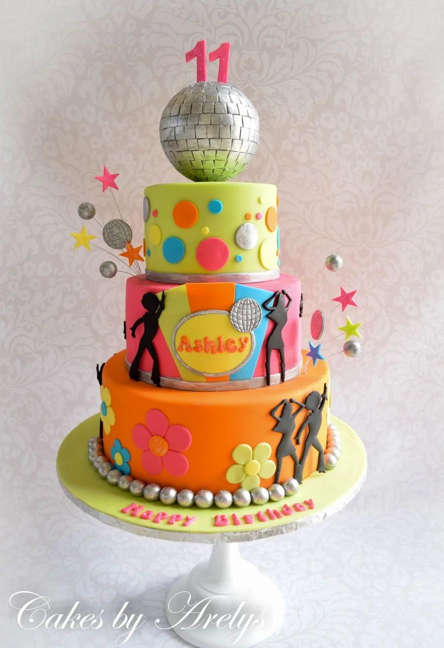 Three-tier disco themed birthday cake in lime green, pink, and orange with a large silver disco ball topper and dancing silhouettes.