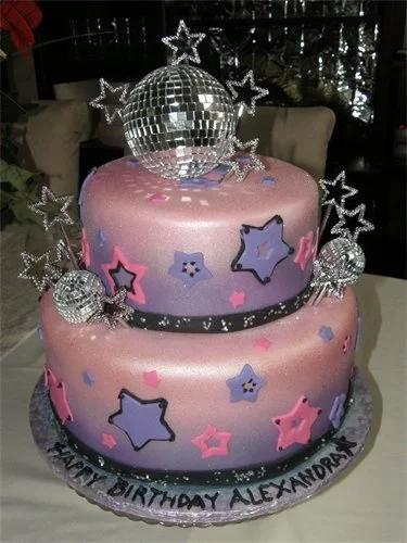 Two-tier disco themed birthday cake with pink and purple gradient fondant, edible stars, and a large silver disco ball topper.
