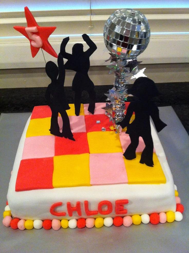 Square disco themed cake with black dancer silhouettes, a disco ball topper, and colorful fondant floor tiles in pink, yellow, and red.
