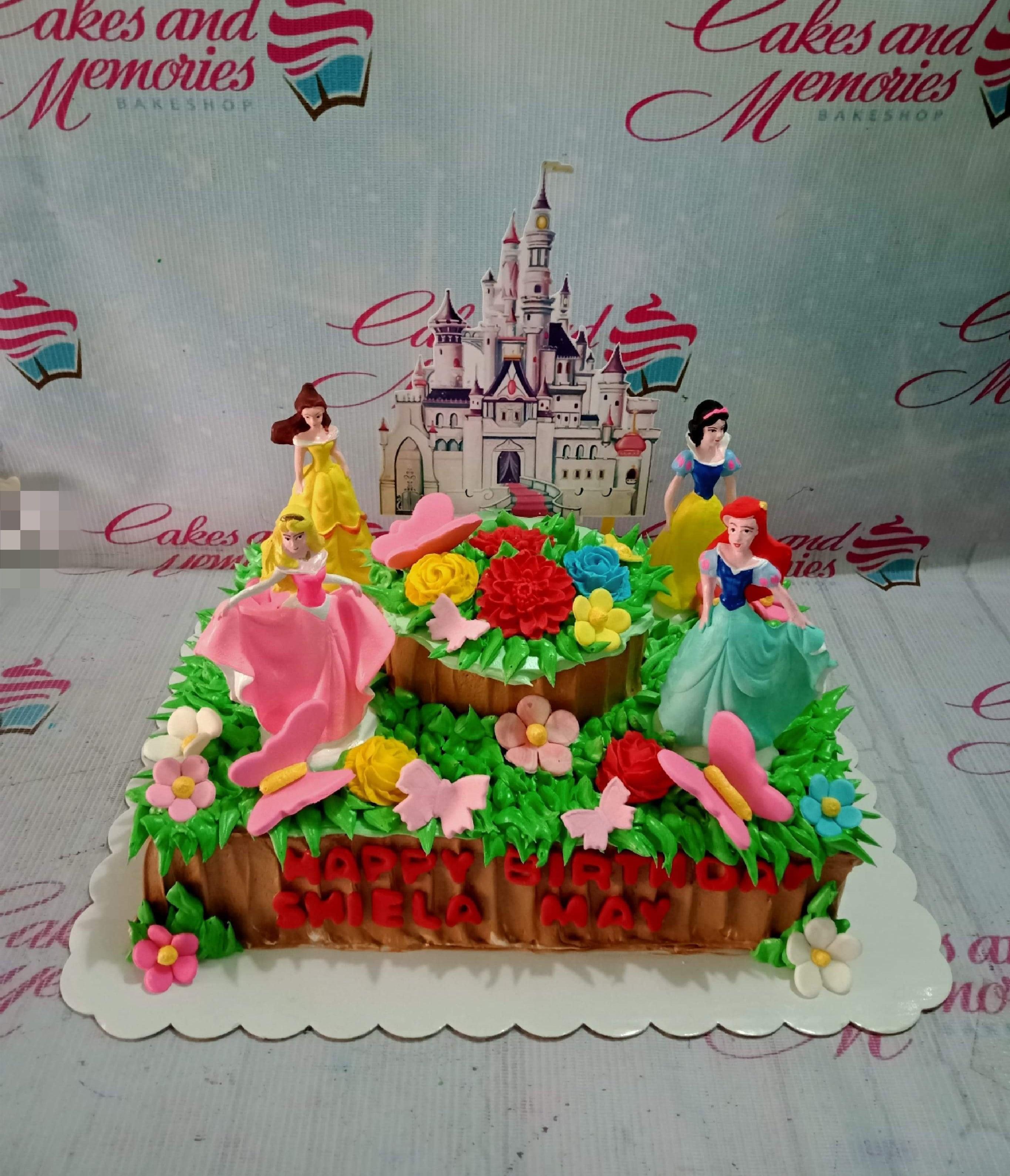 Disney Princess themed rectangle cake with a castle printout, princess figurines, and colorful icing flowers and butterflies.