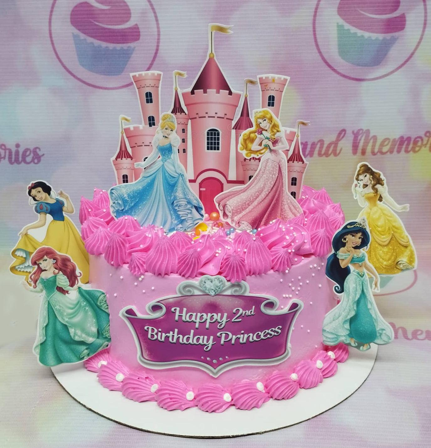 Pink Disney Princess themed birthday cake with Cinderella, Aurora, Belle, Jasmine, Ariel, and Snow White printouts and a pink castle topper.