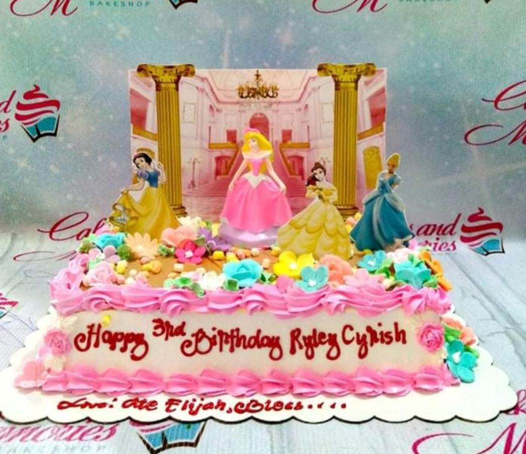 Disney Princess themed rectangle cake with Snow White, Aurora, Belle, and Cinderella toppers, pink icing borders, and colorful icing flowers.