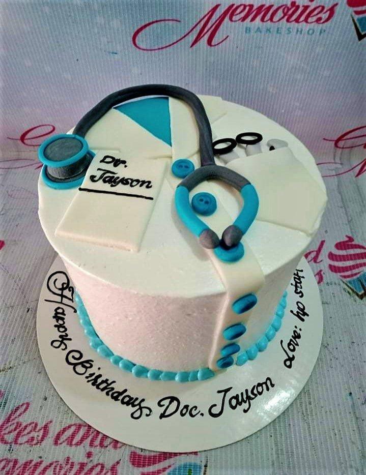 White medical themed birthday cake for a doctor featuring a fondant stethoscope, lab coat details, and blue buttons.