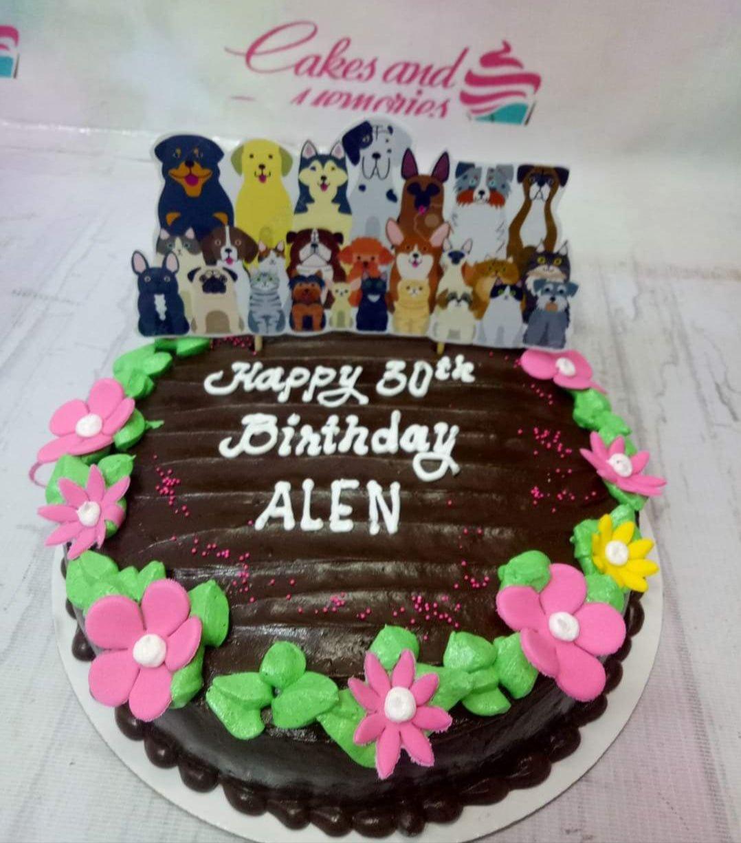 Chocolate birthday cake with pink and yellow icing flowers and a large printout topper featuring various dog and cat breeds.