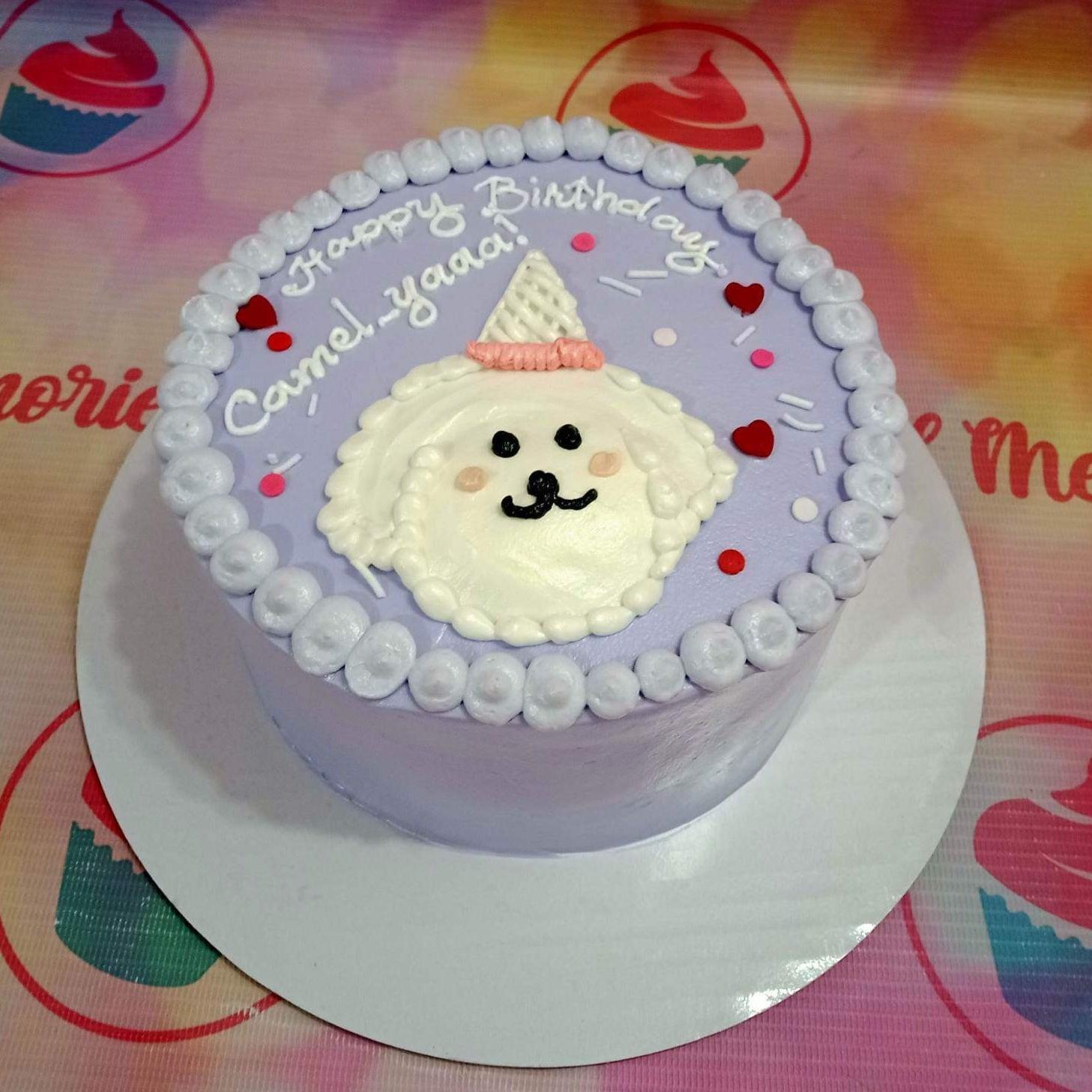Light purple bento cake with a white piped dog face wearing a party hat and red heart sprinkles.