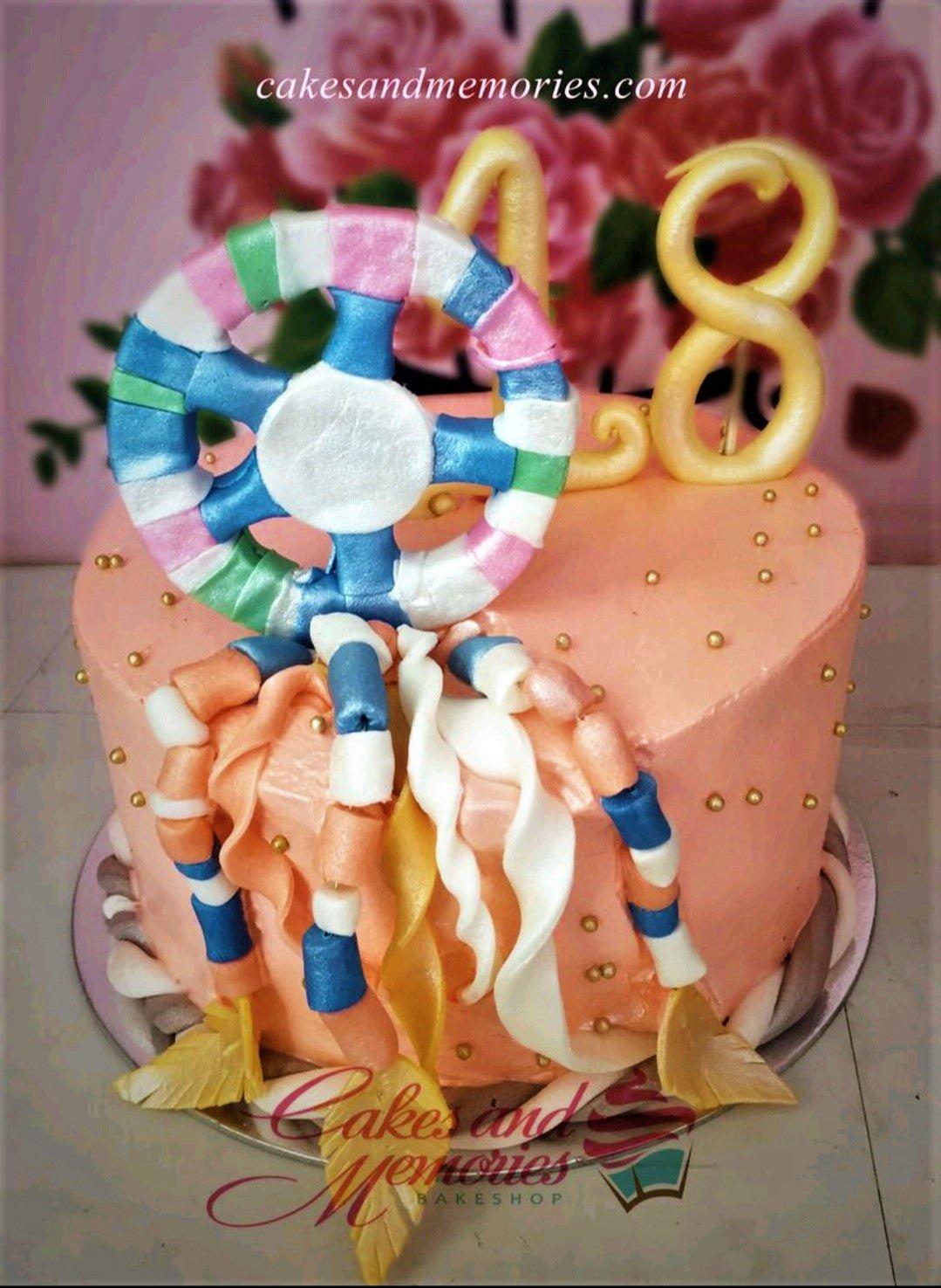 Peach-colored dreamcatcher cake with gold number 18 toppers and gold dragees.