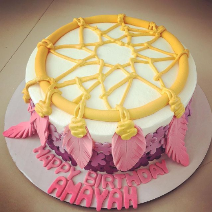 Dreamcatcher themed birthday cake with pink fondant feathers and purple floral ombre side decorations.