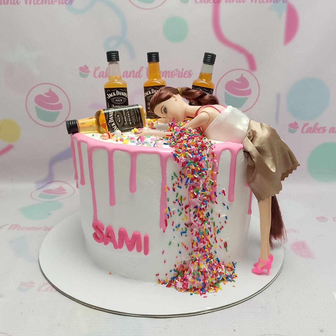 White 1-tier birthday cake with pink drip, a doll figure, mini whiskey bottles, and a cascade of rainbow sprinkles.