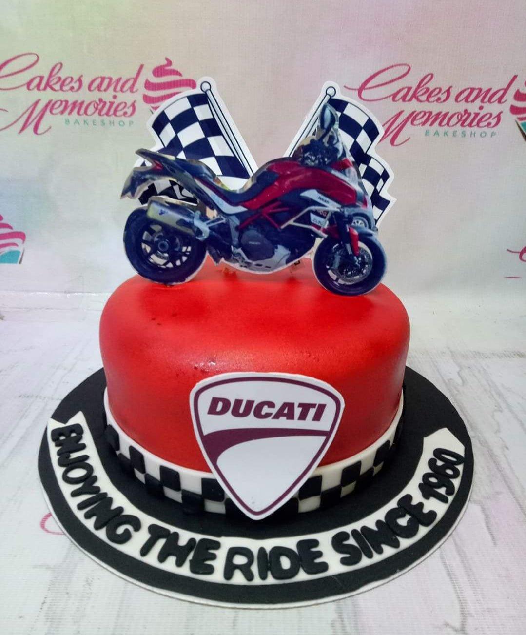 Red Ducati motorcycle themed cake with checkered flag toppers and a large Ducati logo on the side.