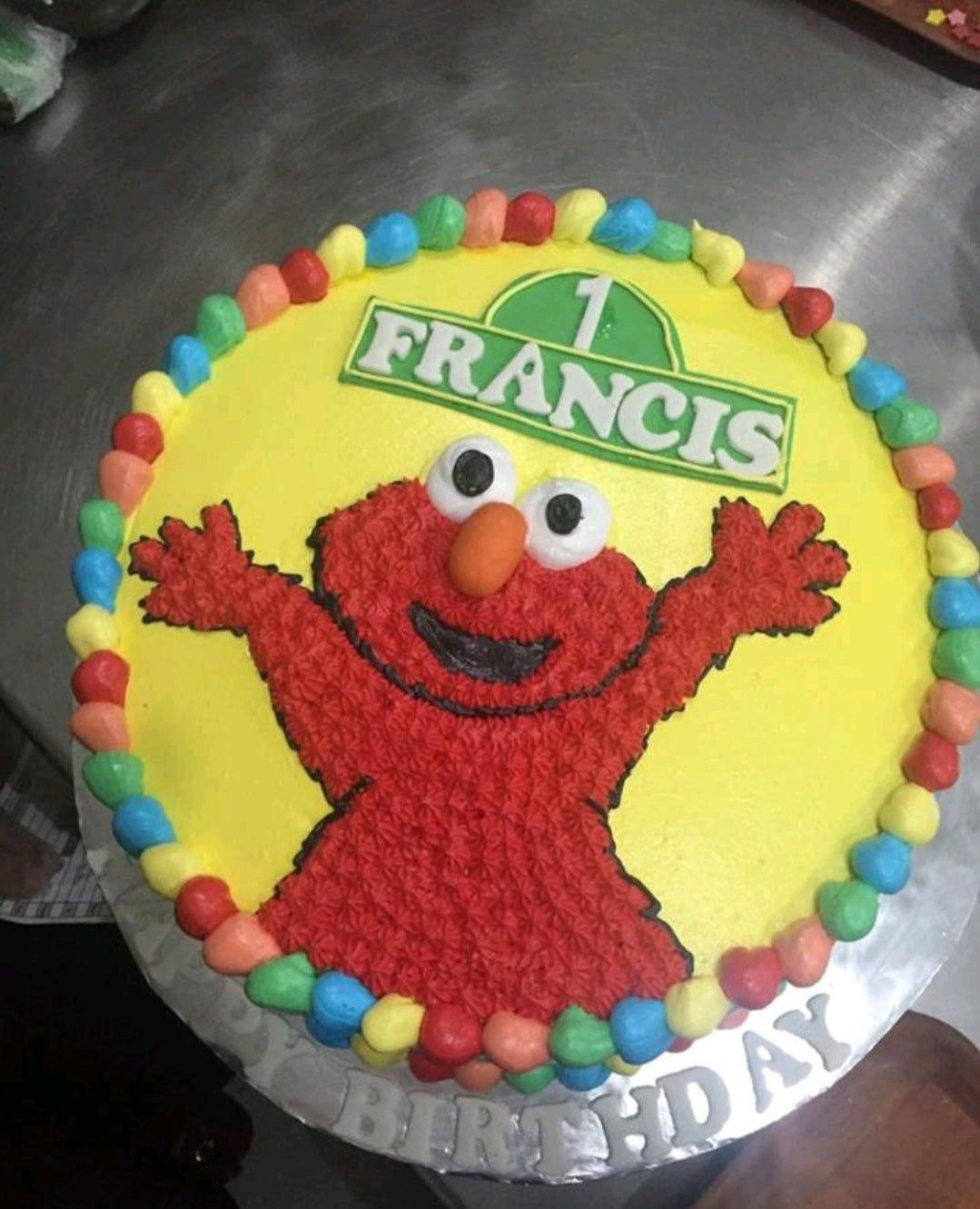 Yellow Elmo themed birthday cake with a large red icing Elmo and colorful border rosettes.