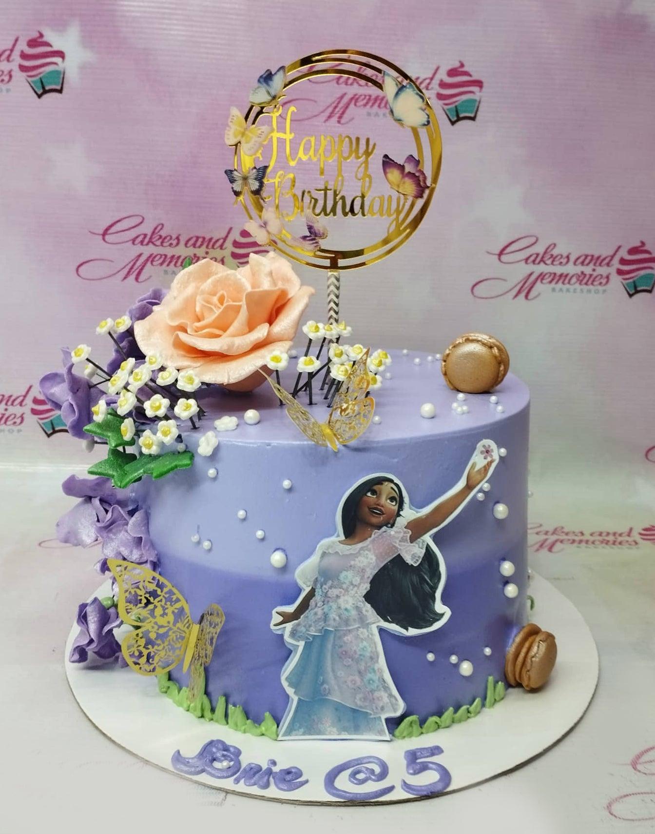 Purple Encanto Isabela themed cake with a large peach rose, purple flowers, gold butterflies, and a character printout.