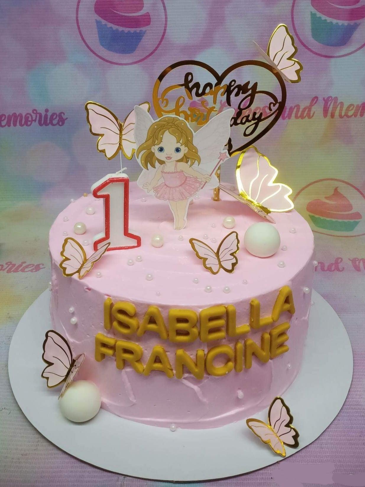 Pink fairy-themed birthday cake with a 3D fairy printout, gold butterflies, and a gold heart topper for Isabella Francine's 1st birthday.