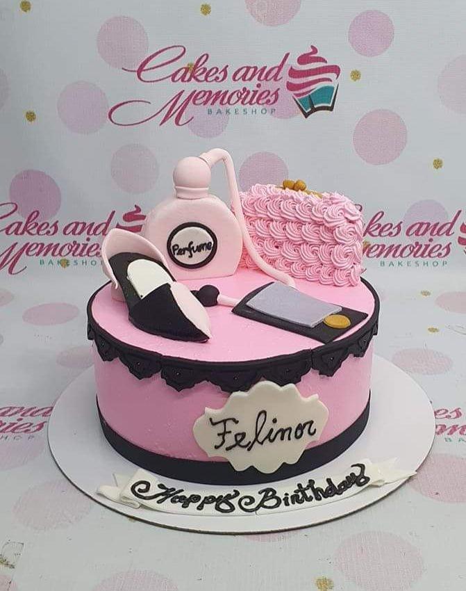 Pink fondant cake with 3D edible perfume bottle, high heel shoe, and makeup bag toppers for a fashion-themed birthday.