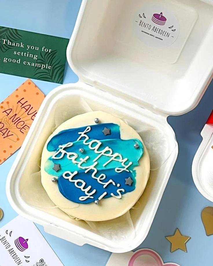 Bento cake for Father's Day with blue and teal palette knife icing strokes, silver dragees, and grey fondant stars.