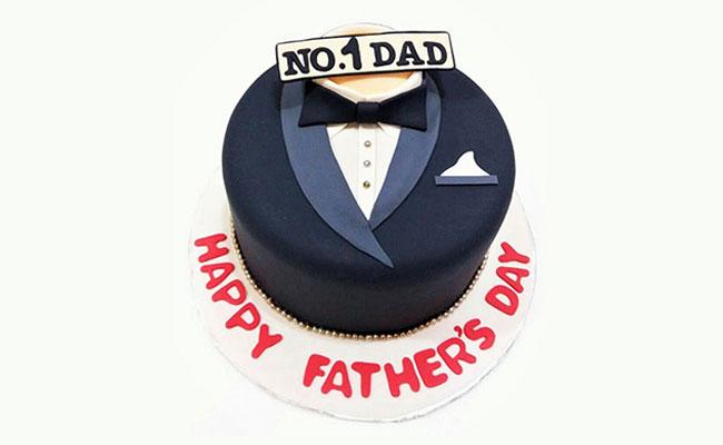 Navy blue tuxedo fondant cake for Father's Day with a black bow tie and No. 1 Dad topper on a white base board.