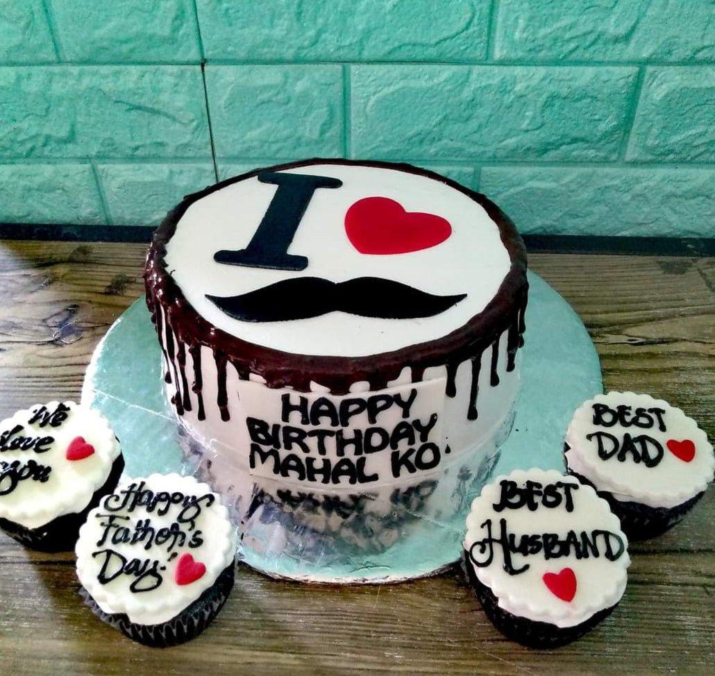 White 1-tier cake with chocolate drip, black mustache topper, and red heart, surrounded by four matching cupcakes for Father's Day.