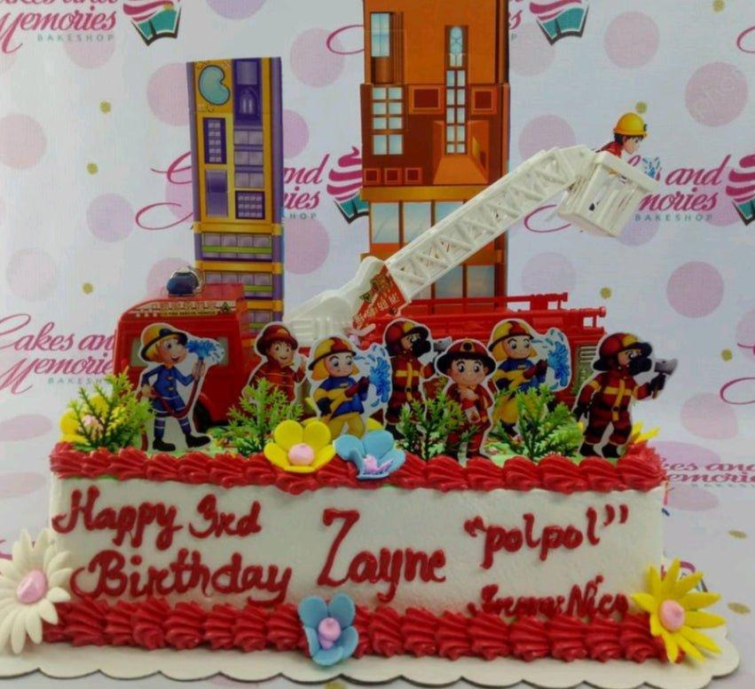 Firefighter themed rectangle cake with red icing borders, fire truck toy, and firefighter character printouts for a 3rd birthday.