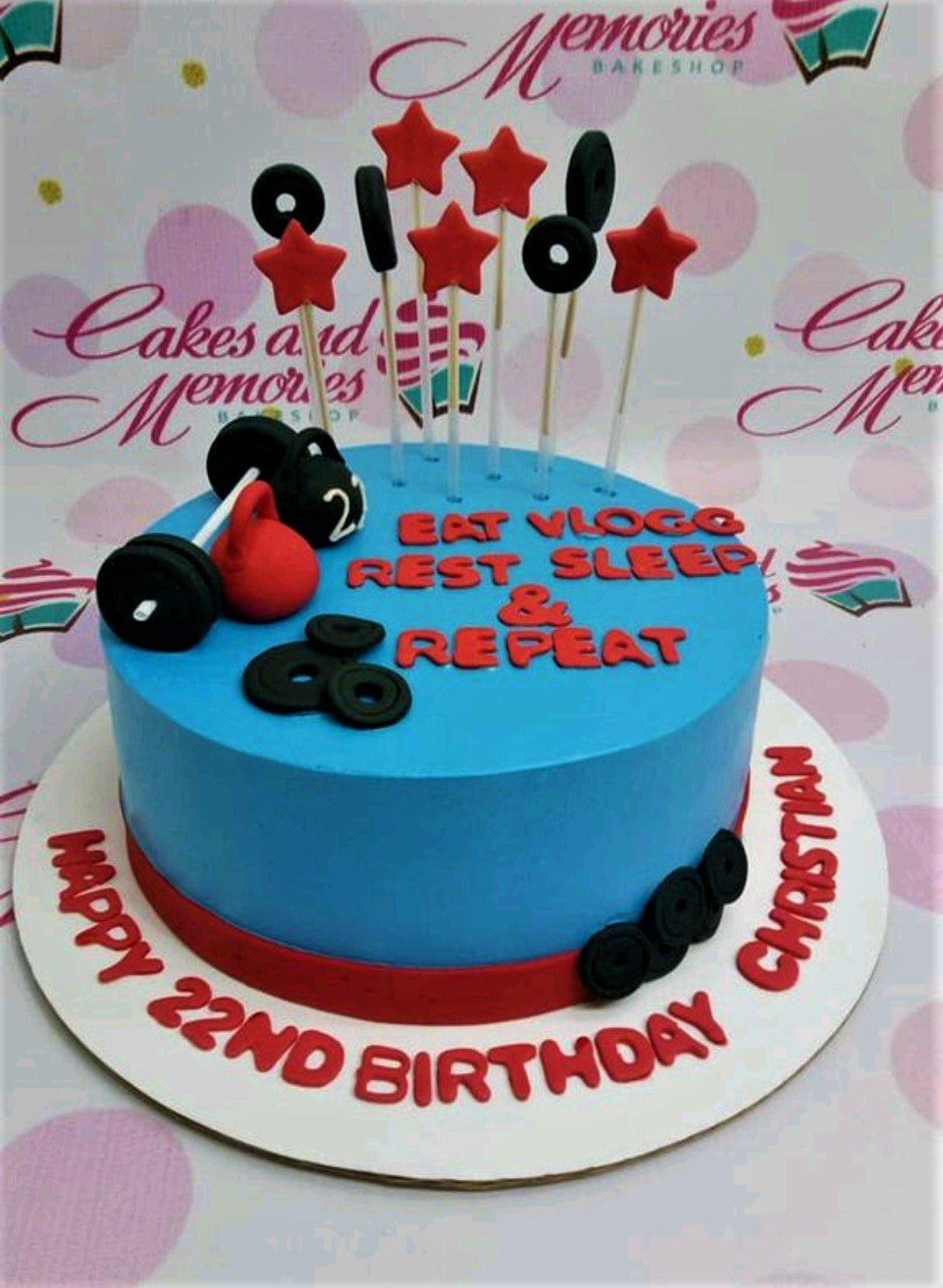 Blue fitness themed birthday cake with red kettlebell, black dumbbells, and weight plate toppers for a 22nd birthday.