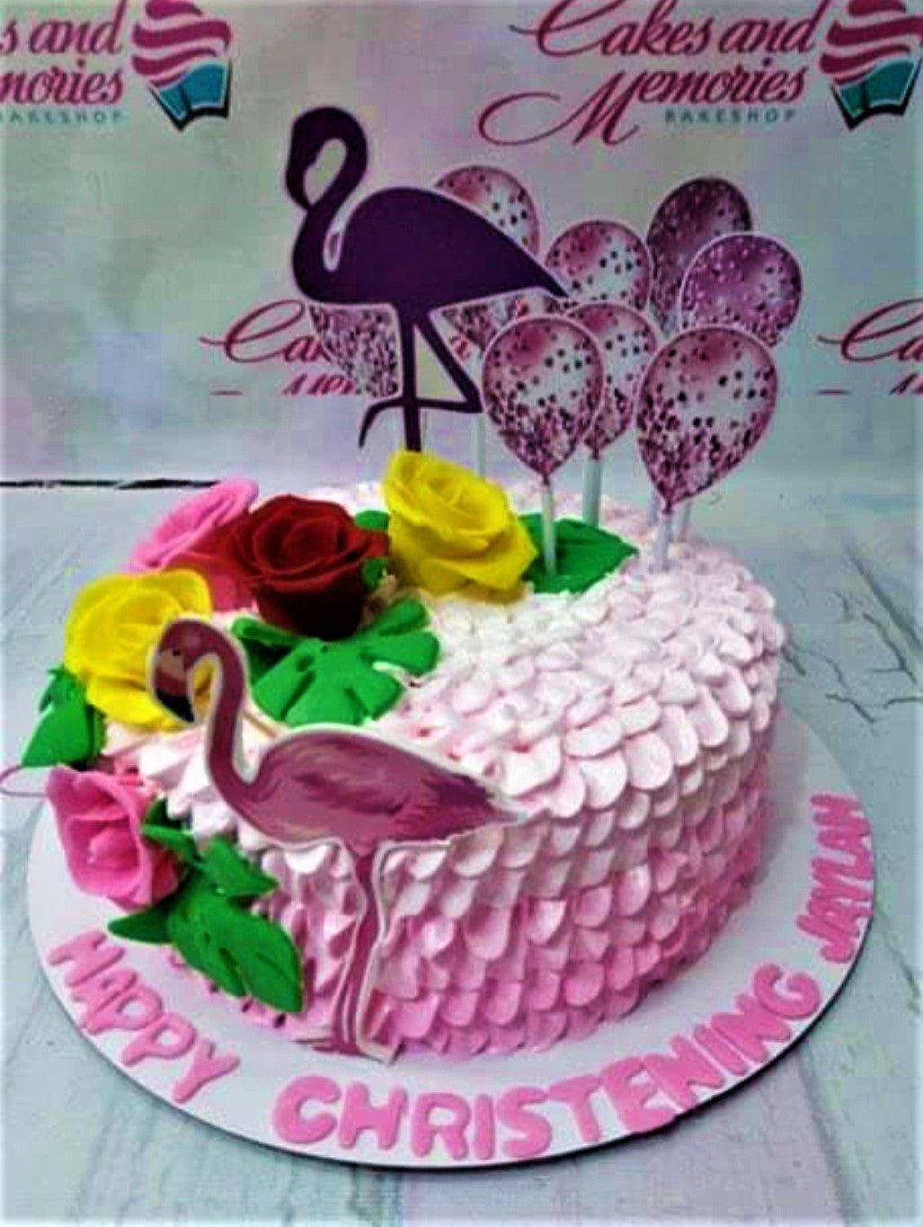 Pink flamingo themed christening cake with pink icing ruffles, edible roses, and flamingo printouts.