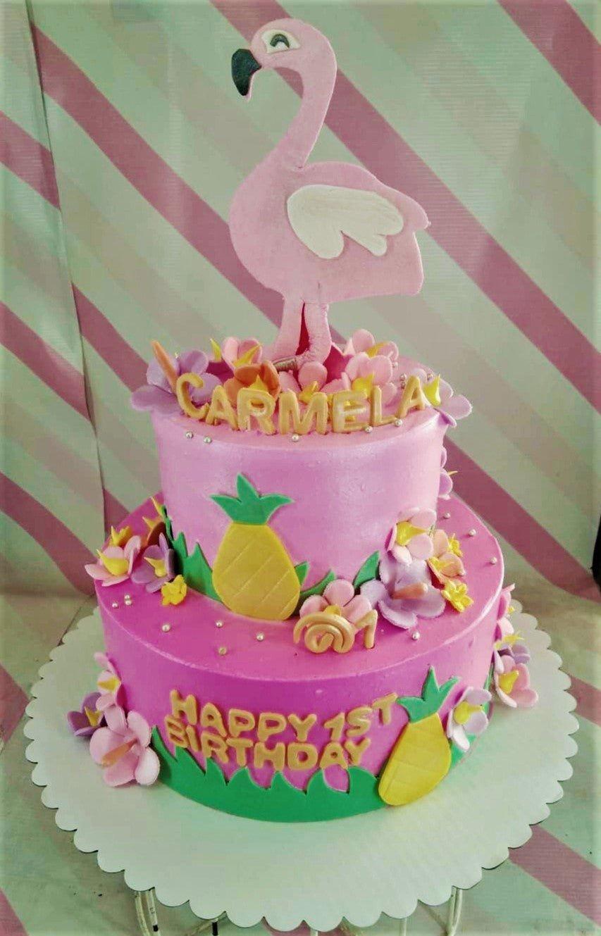 Two-tier pink tropical flamingo birthday cake with fondant pineapples, flowers, and a large pink flamingo topper.