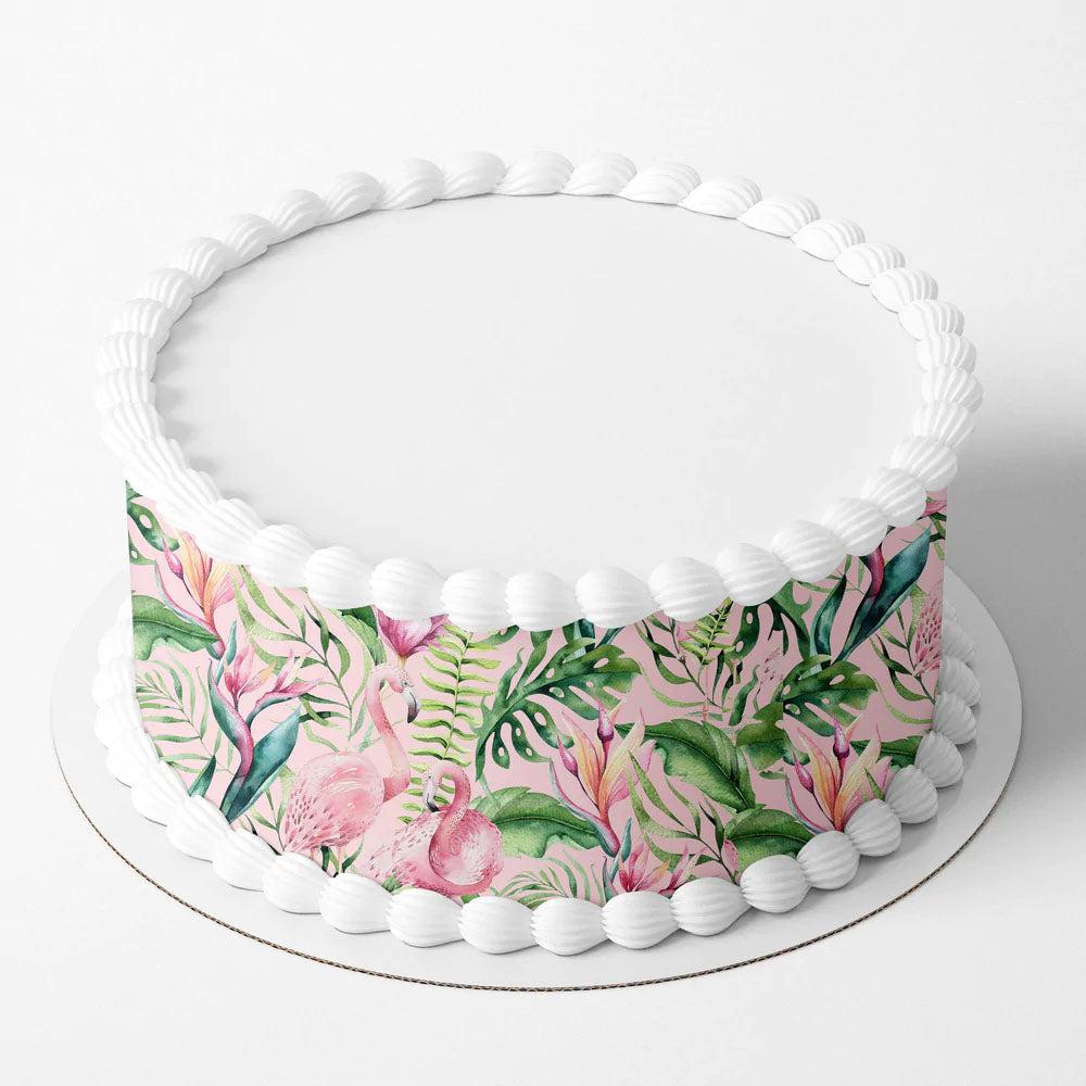 Single tier pink tropical flamingo cake with white icing borders and a printed floral wrap featuring green leaves and pink flowers.