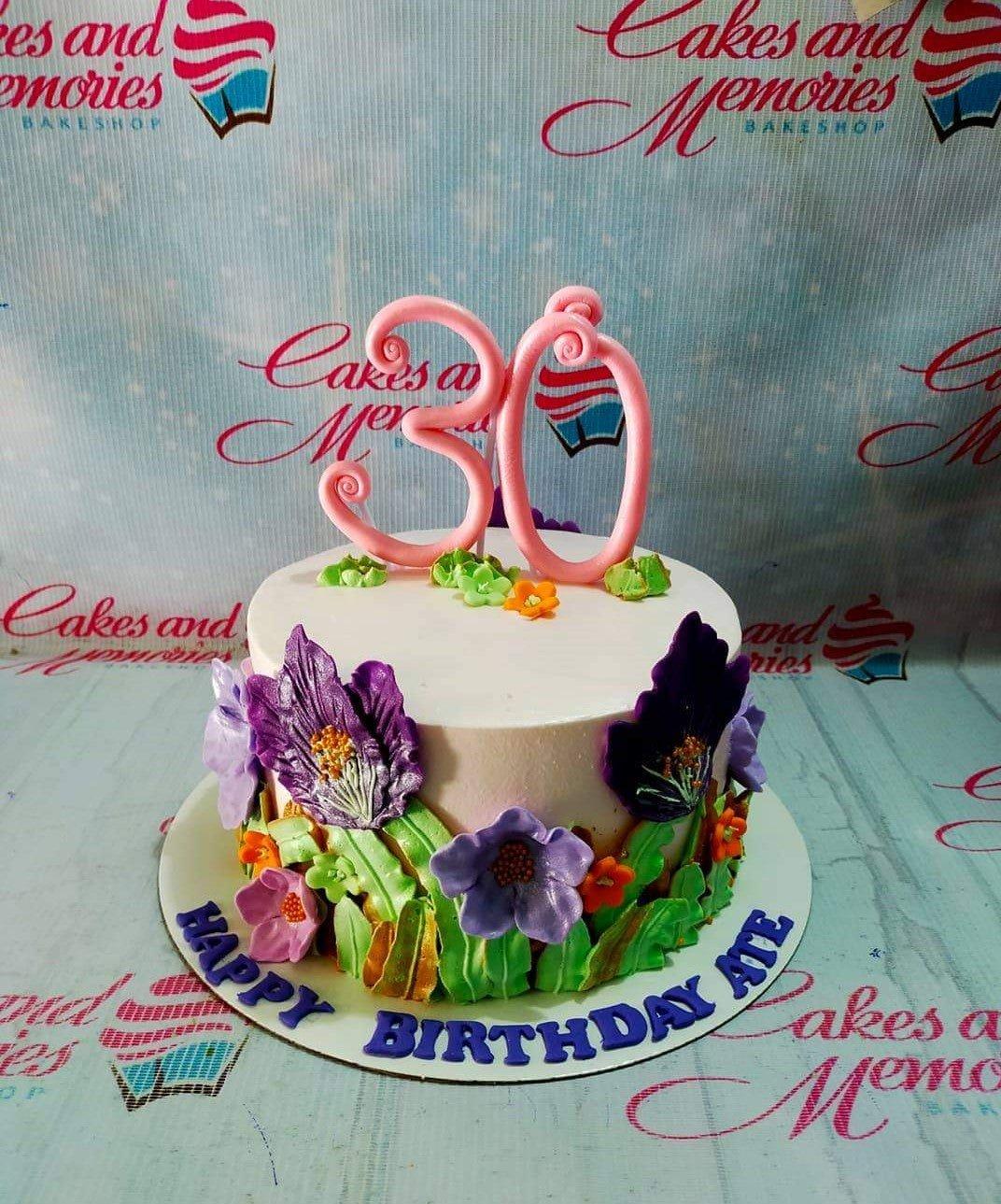 White 1-tier birthday cake with large purple and orange gumpaste flowers, green leaves, and a pink number 30 topper.