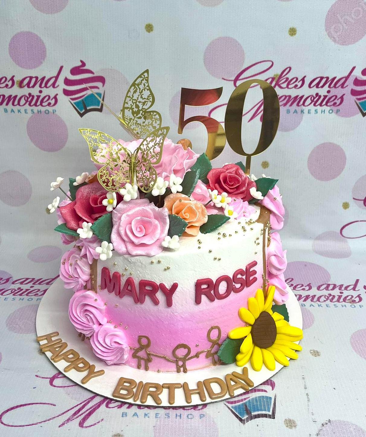 Pink and white gradient floral cake with gold butterflies, a large gold 50 topper, and a sunflower accent.