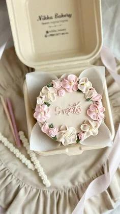 Bento cake with ivory icing, a wreath of pink and white buttercream flowers, and '5 months' written in the center.