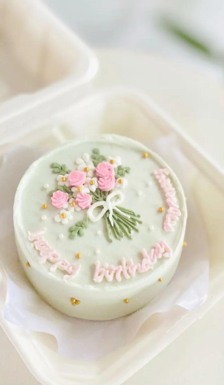 Mint green bento cake with a piped icing flower bouquet and pink Happy Birthday message