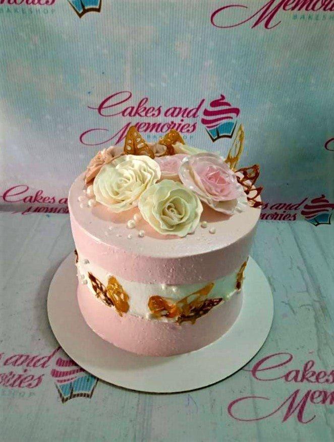 Pink and white floral cake with edible roses, isomalt butterflies, and pearl sprinkles.