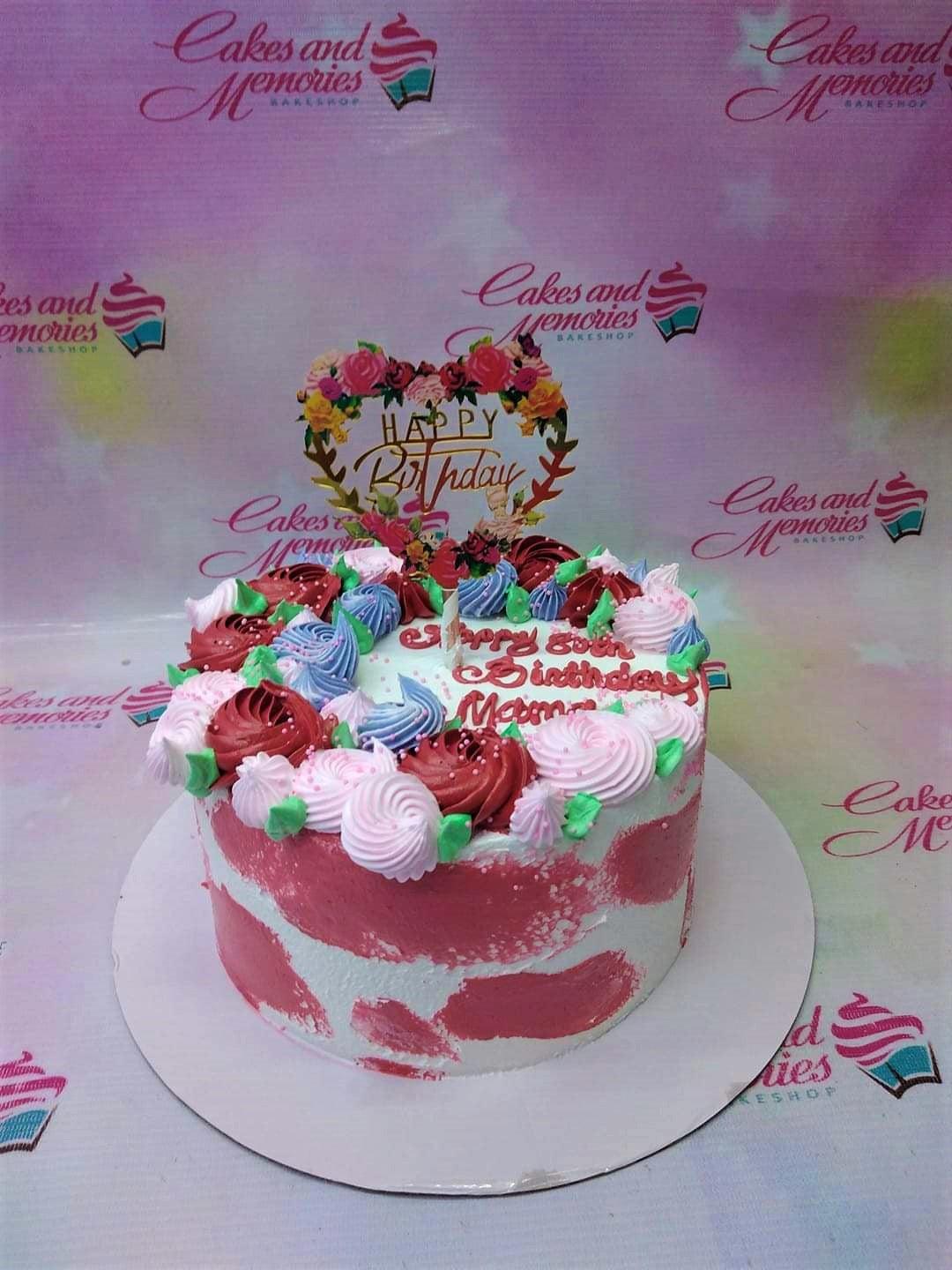 Pink and white textured birthday cake with colorful icing rosettes and a floral heart topper