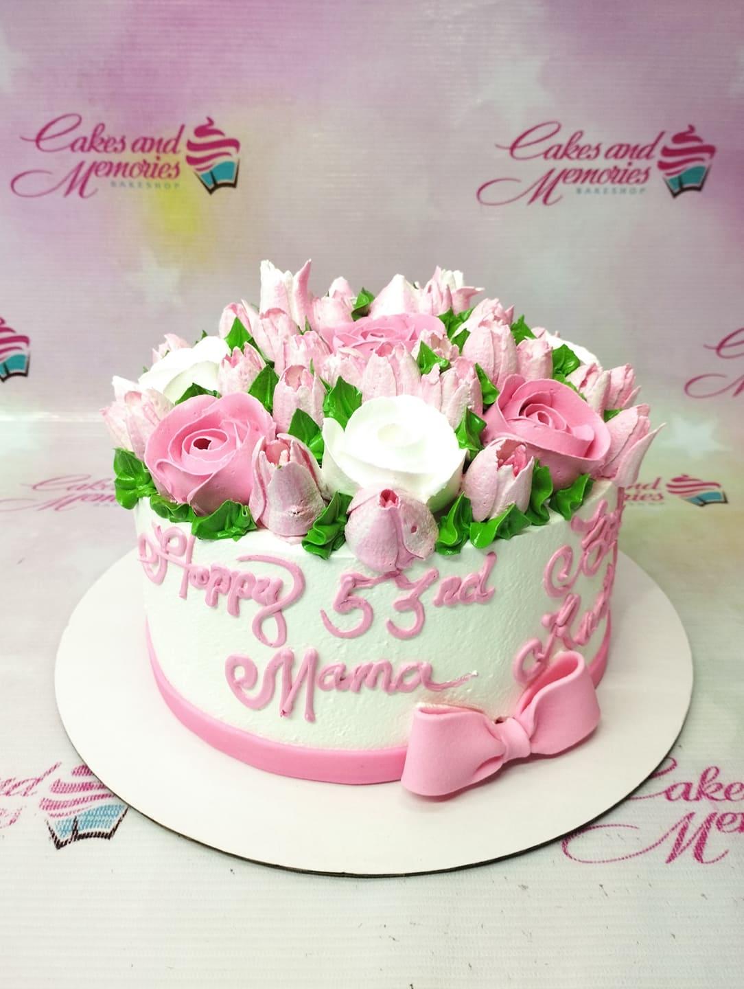 White 1-tier birthday cake for Mama with pink and white icing roses and a pink fondant bow.