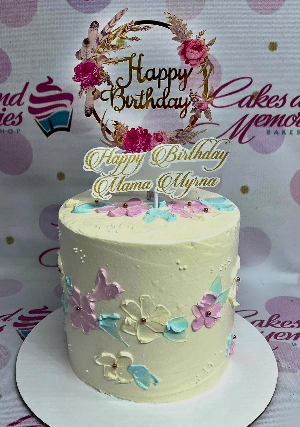 White 1-tier birthday cake with palette knife floral icing in pink, teal, and yellow, topped with a floral wreath and custom name topper.