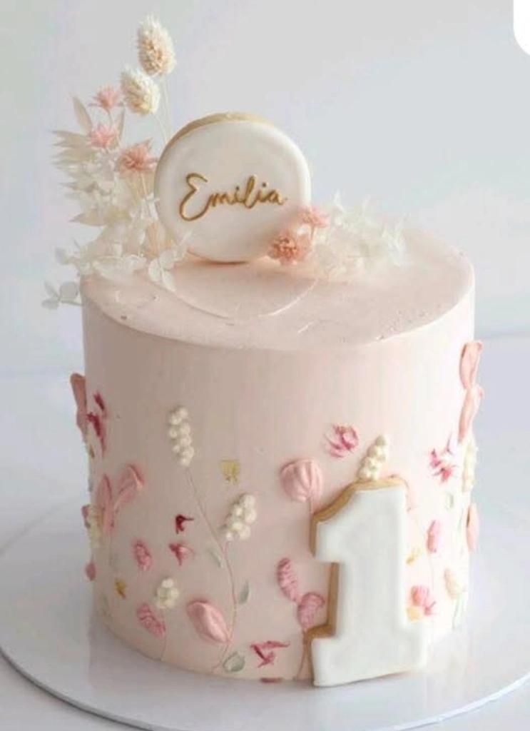Elegant light pink 1-tier birthday cake with palette knife floral icing, a white number one cookie, and a personalized name topper.