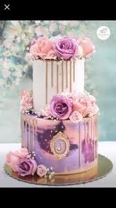 A multicolor 2-tier cake featuring pink and purple roses and gold icing drip.