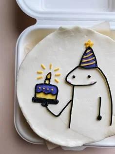 White bento cake featuring a hand-drawn Flork character wearing a purple party hat and holding a small purple birthday cake.