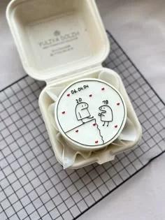 White bento cake with minimalist Flork character drawings and red hearts in a compostable box.