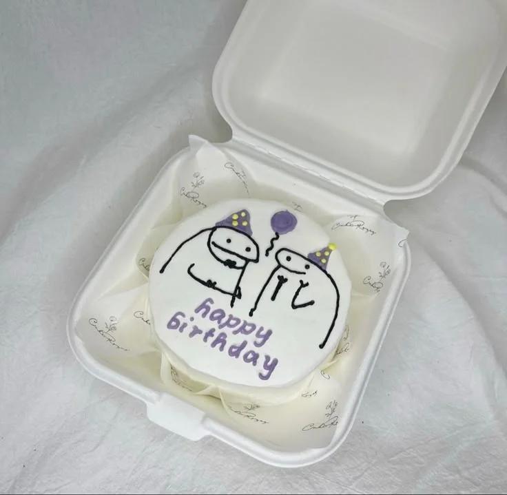 White bento cake in a box featuring two hand-drawn flork characters with purple party hats and a purple balloon.