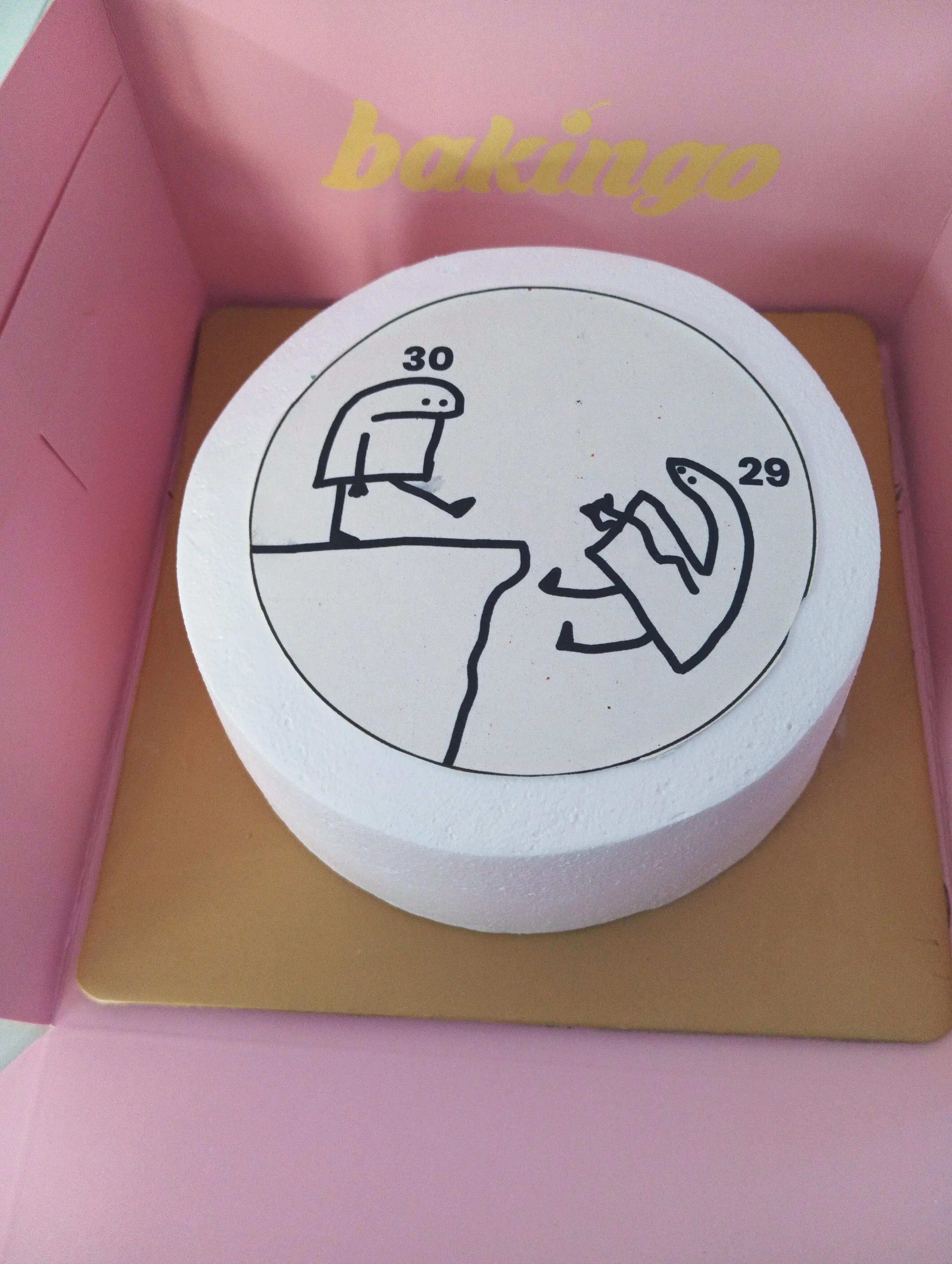 White bento cake with a humorous Flork of Cows meme printout showing one character kicking another off a cliff with ages 29 and 30.