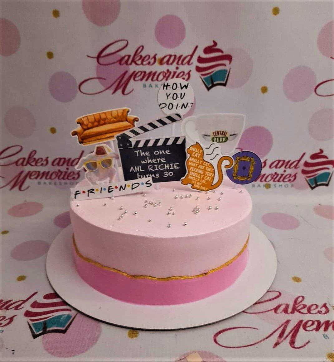 Pink Friends themed birthday cake with iconic show elements like the orange couch, Central Perk mug, and smelly cat printouts.