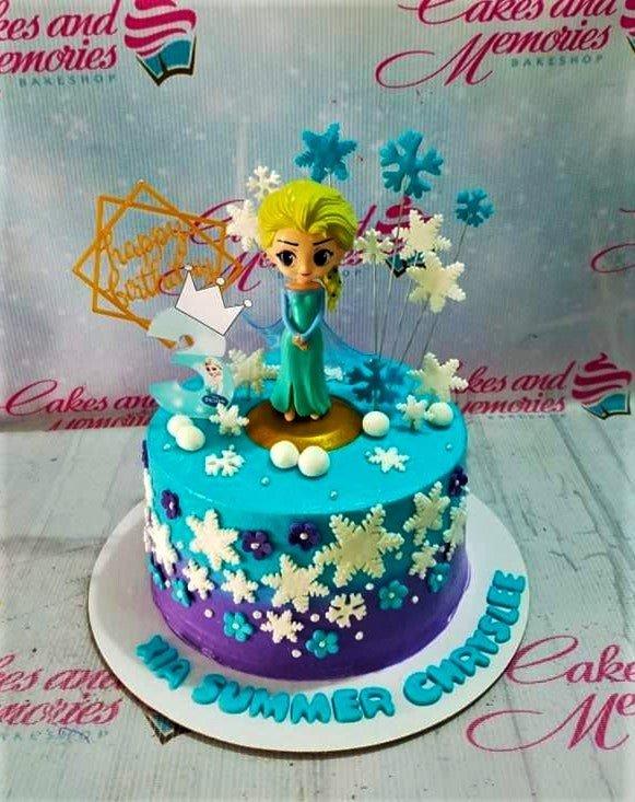 Frozen Elsa themed birthday cake with blue and purple gradient icing, snowflake toppers, and a 3D Elsa figurine.