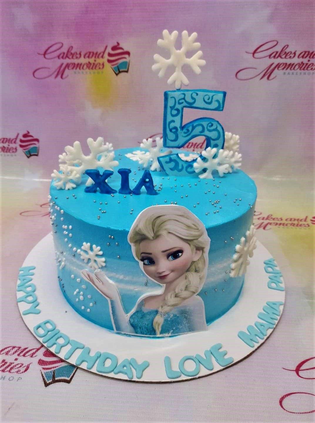 Blue Frozen themed birthday cake for Xia featuring Elsa printout, fondant snowflakes, and a large number 5 topper.