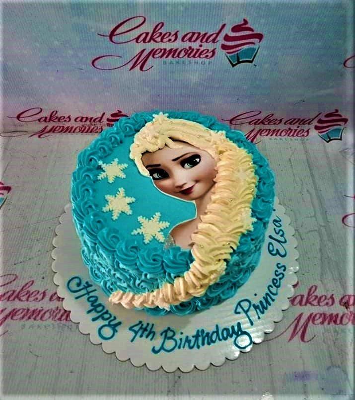 Blue Frozen Elsa birthday cake with piped icing ruffles and a large Elsa printout topper.