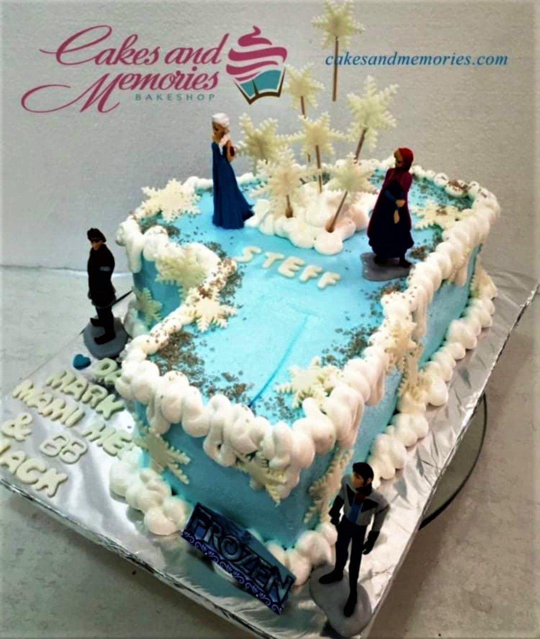 Light blue Frozen themed rectangle cake with Elsa, Anna, Kristoff, and Hans figurines, snowflake toppers, and white icing clouds.