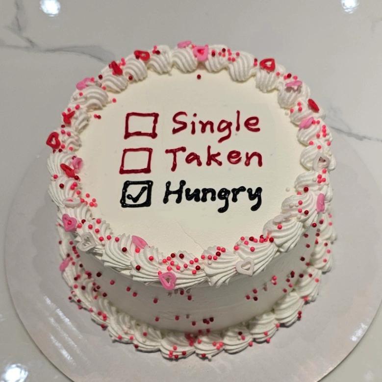 White bento cake with piped icing borders, pink and red heart sprinkles, and a humorous relationship status checklist message.