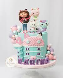 Teal Gabby's Dollhouse cake with 3D fondant characters, a pink house panel, and pastel balloon clusters